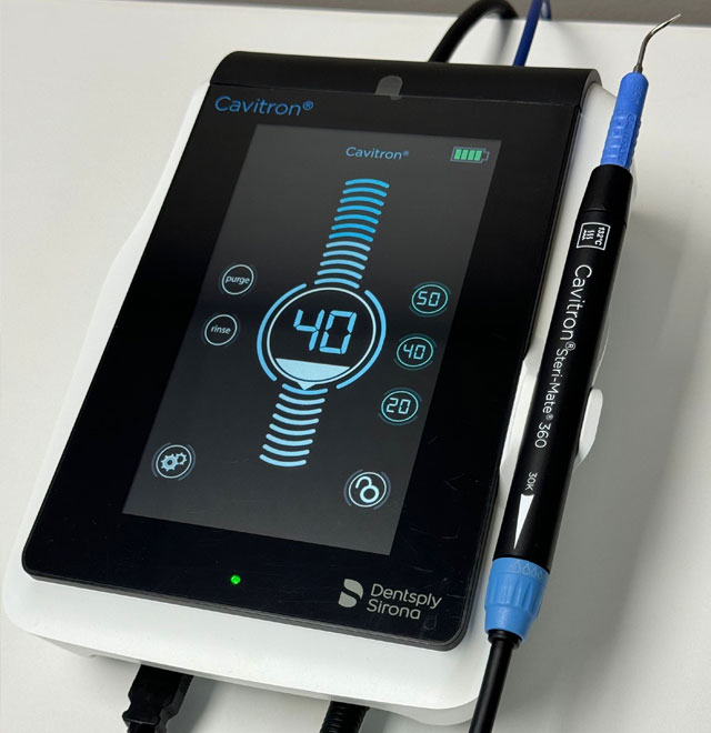 The image shows a digital dental device with a screen displaying various measurements, accompanied by a stylus and a power cable.