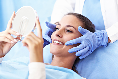 A person receiving a medical treatment with a professional assistant using a magnifying mirror.